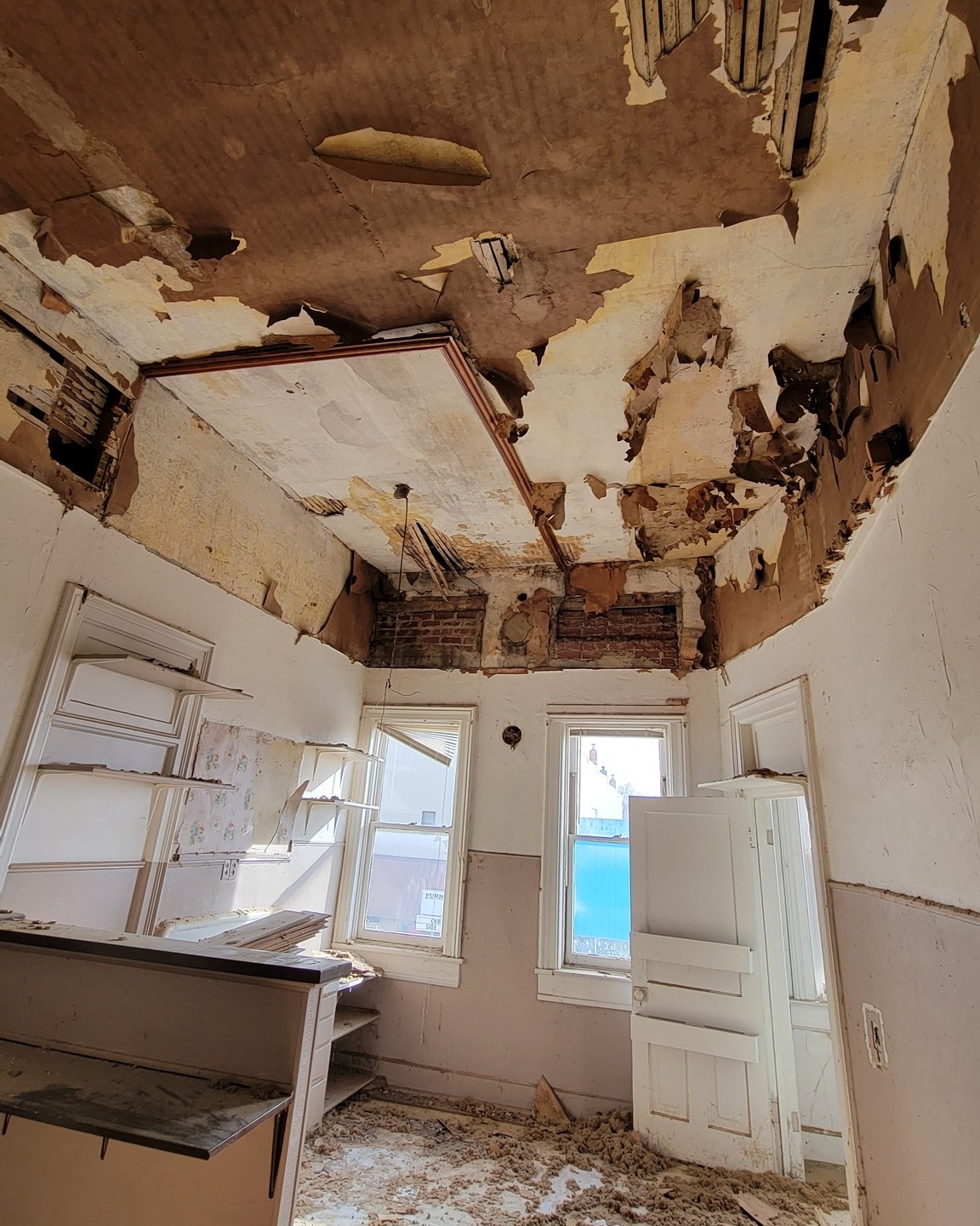 It's amazing how much more spacious a room seems with the drop ceiling torn out -- although you never quite know what you'll find. In this case, you can see the original height of the windows, which we'll be restoring them back to.